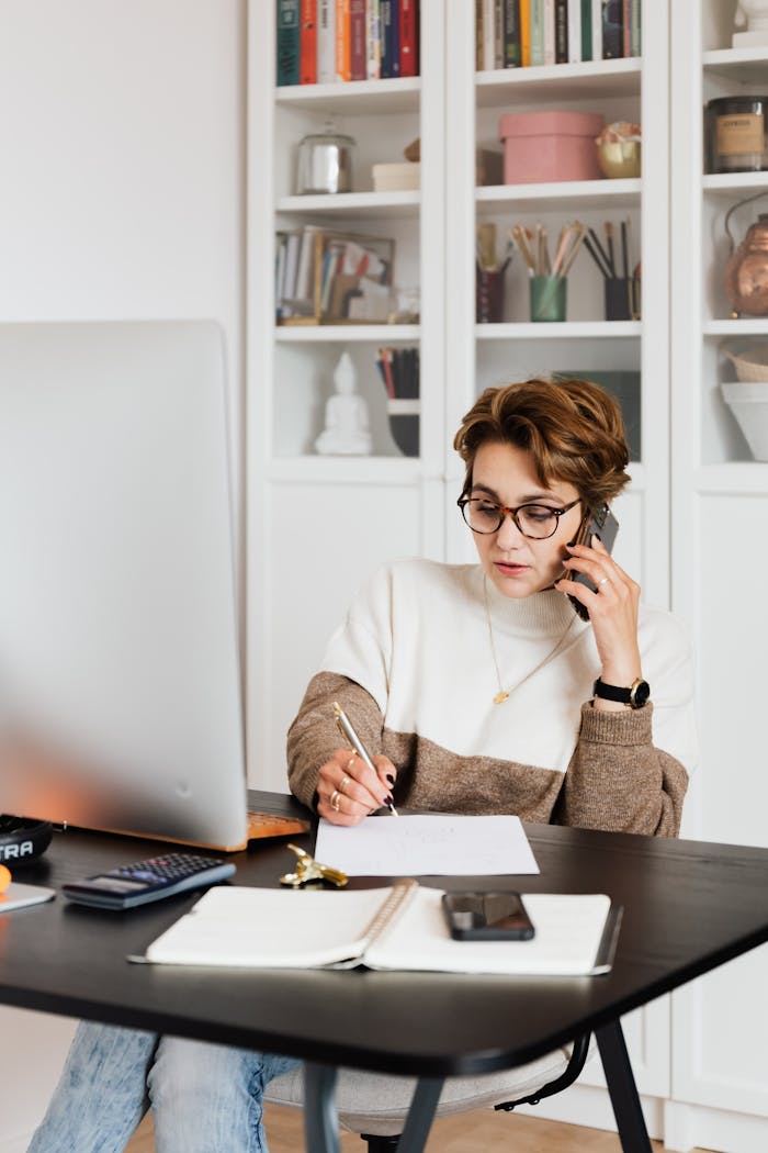 Focused businesswoman in modern office multitasking efficiently while on a phone call.